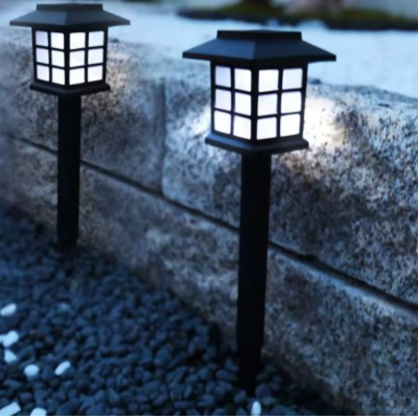 lampy solarne LED ogrodowe przy murku z kamienia na tle żwiru.png