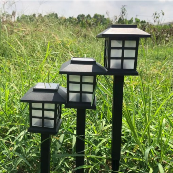 trzy solarne lampy LED w różnych wysokościach w ogrodzie na tle trawy.png